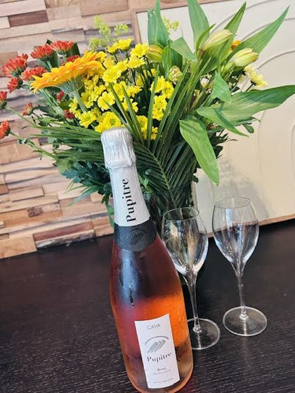 Fles cava met glazen en bloemen op tafel bij De Nisse